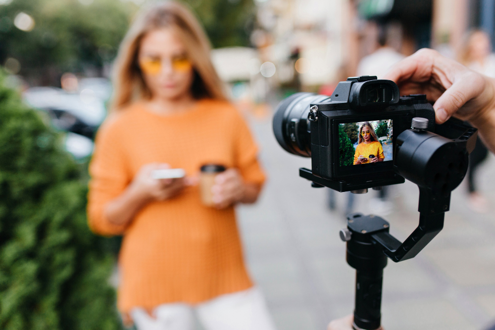 Free photo blur portrait of woman in yellow glasses with black camera in focus
