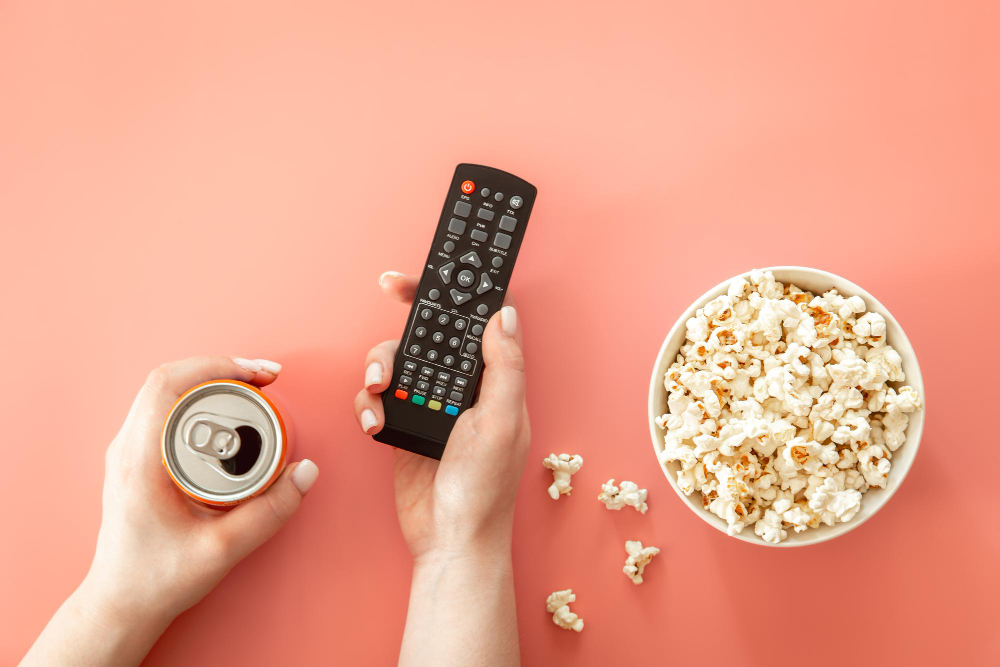 Photo remote and drink in female hands watching movies flat lay