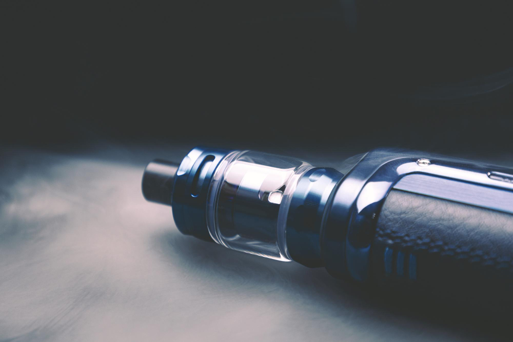 Photo vape on a black background in smoke an electronic cigarette for smoking nicotine a lot of steam from a cigarette