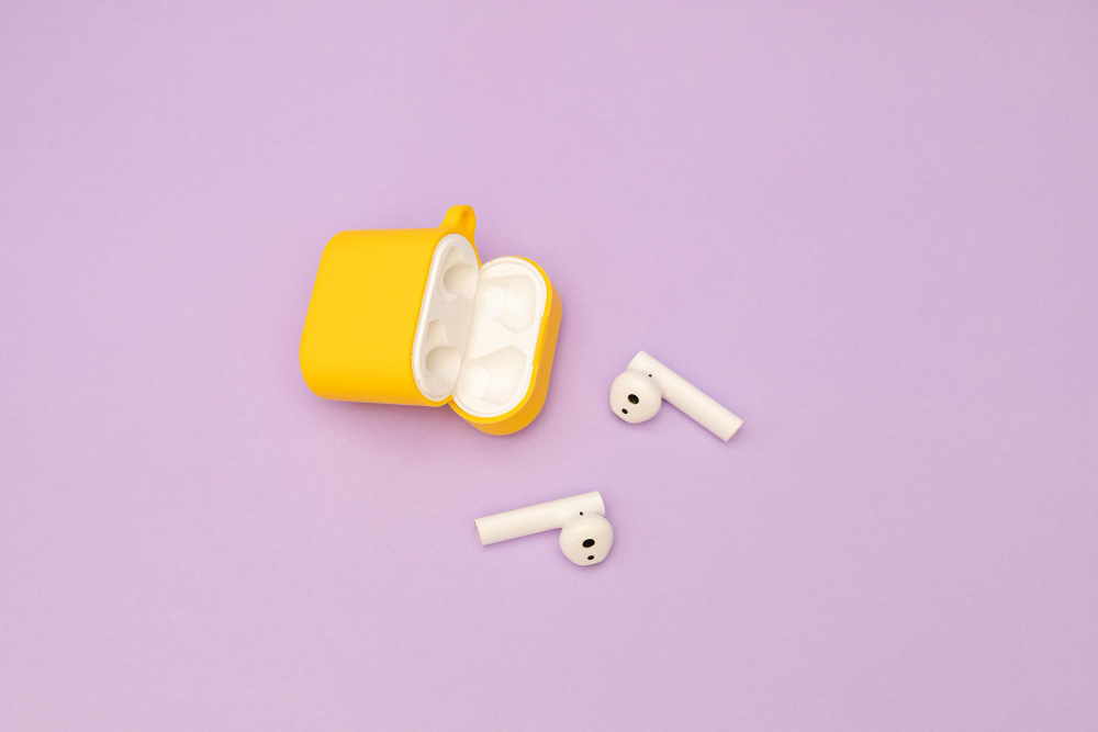 Wireless headphones in a yellow case on a purple background
