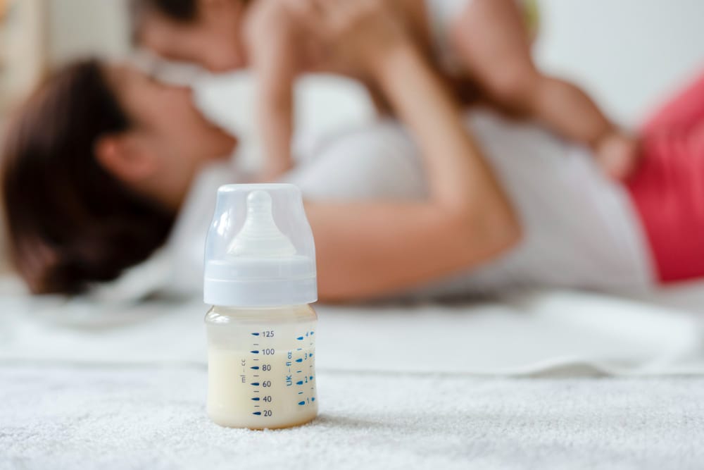 Free photo baby formula with mom and baby in the background