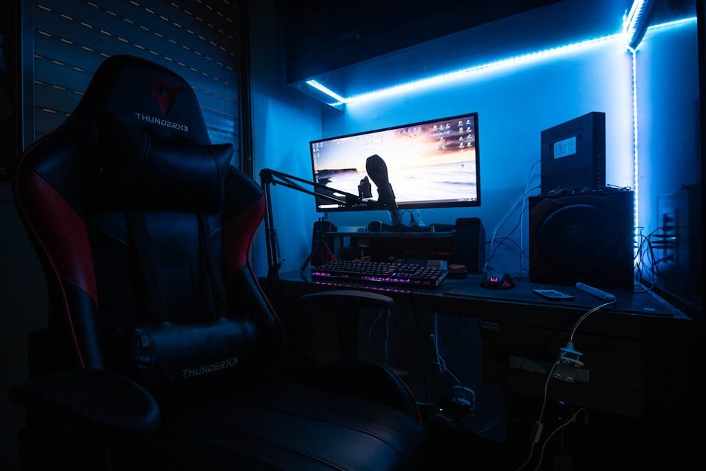 Desktop Computer with Speakers and Gaming Chair in a Room with Blue Light