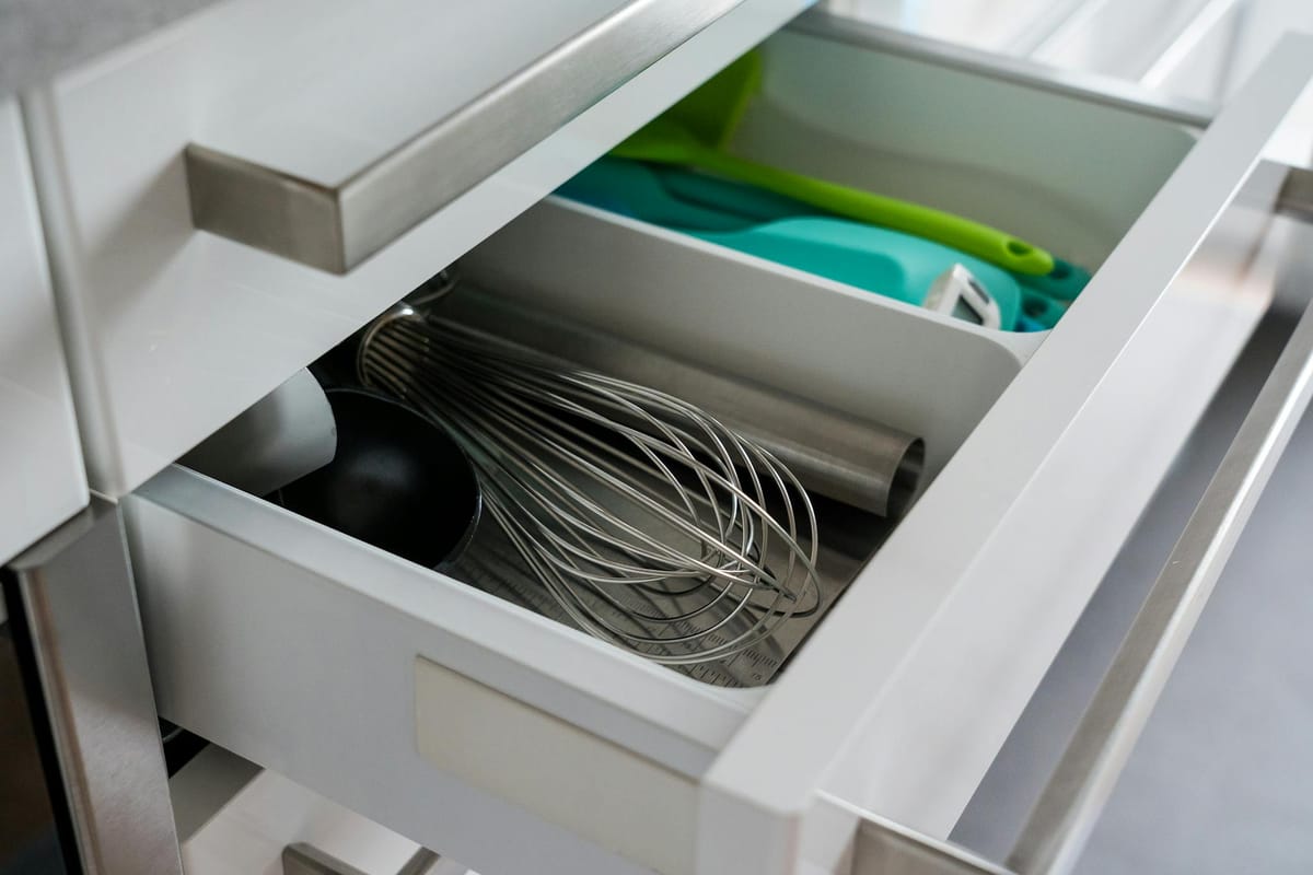 Open kitchen drawer showcasing organized utensils including a whisk and scoop.