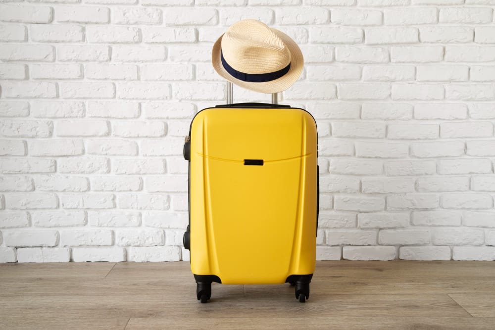yellow travel suitcase with straw hat