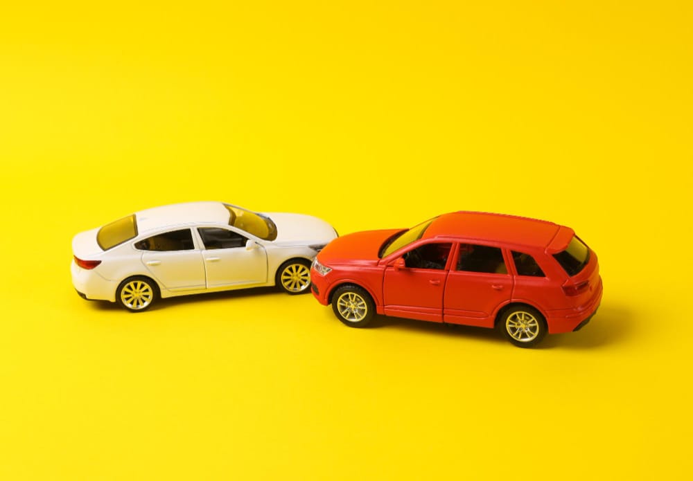 Two mini toy car crash on a yellow background incident car traffic accident