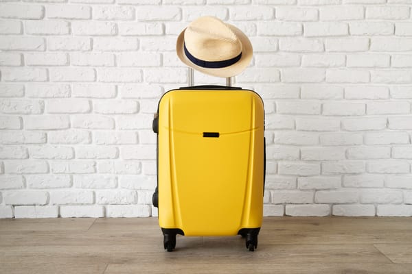 yellow travel suitcase with straw hat