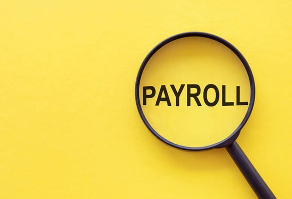 Yellow background a magnifying glass with the text payroll financial concept
