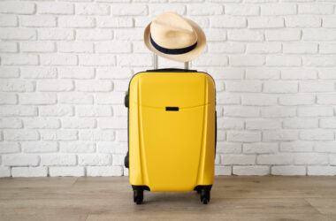 yellow travel suitcase with straw hat