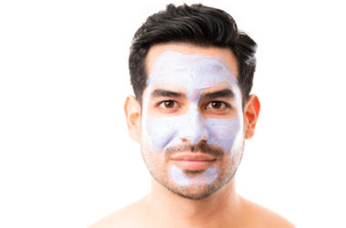 Closeup of a good looking man with facial mask against white background