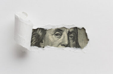 torn paper with money behind it.
