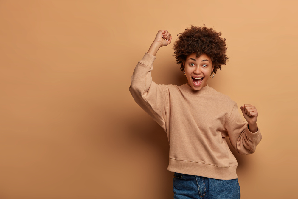 Triumphing joyful woman celebrates win, feels lucky and upbeat