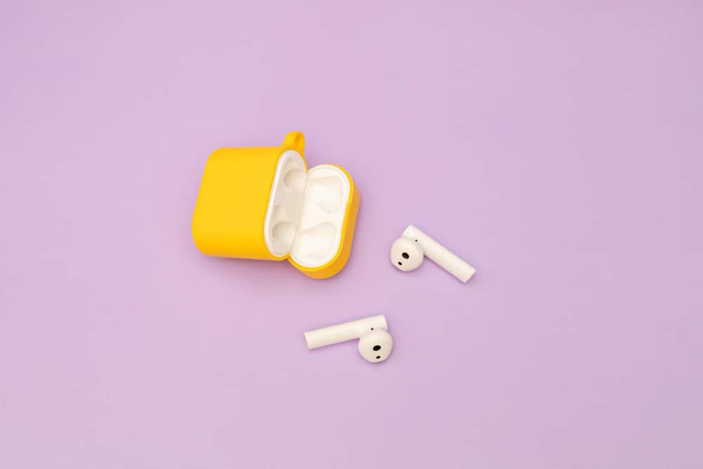 Wireless headphones in a yellow case on a purple background 