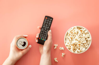 Photo remote and drink in female hands watching movies flat lay