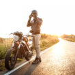 Young handsome man posing near his motorbike at countryside road.