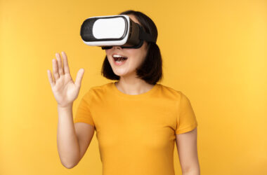 Free photo girl in vr beautiful young asian woman using virtual reality glasses and playing chatting virtually standing over yellow background