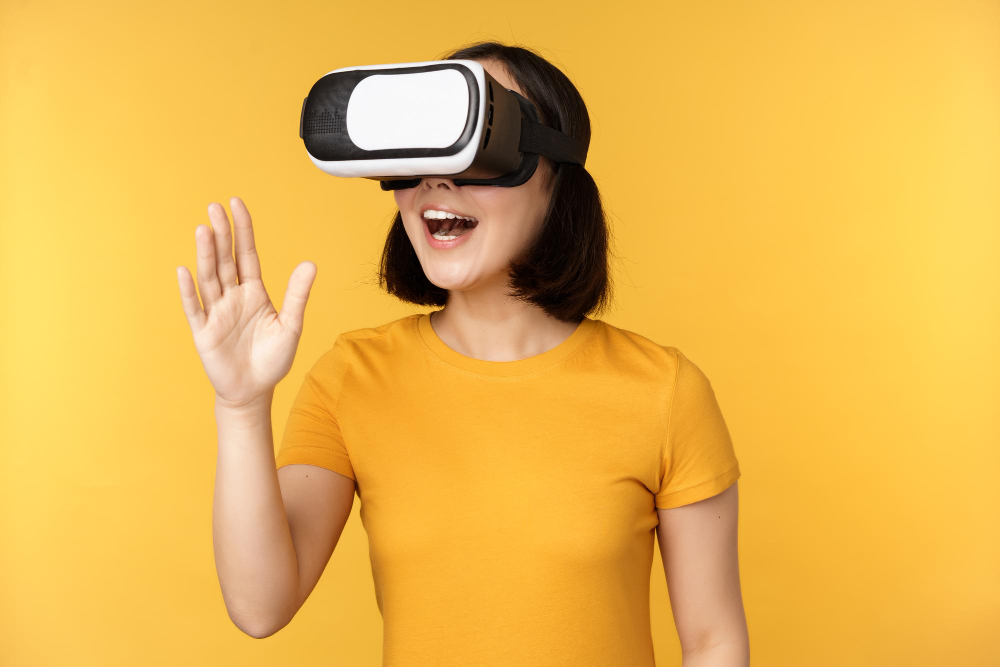 Free photo girl in vr beautiful young asian woman using virtual reality glasses and playing chatting virtually standing over yellow background
