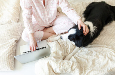 Photo mobile office at home. young woman in pajamas sitting on bed with pet dog working using on laptop pc computer at home. lifestyle girl studying indoors. freelance business quarantine concept.