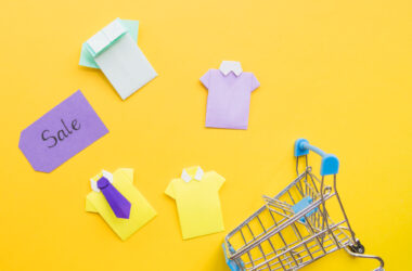 Free photo colourful toy paper shirts near shopping trolley and sale tag