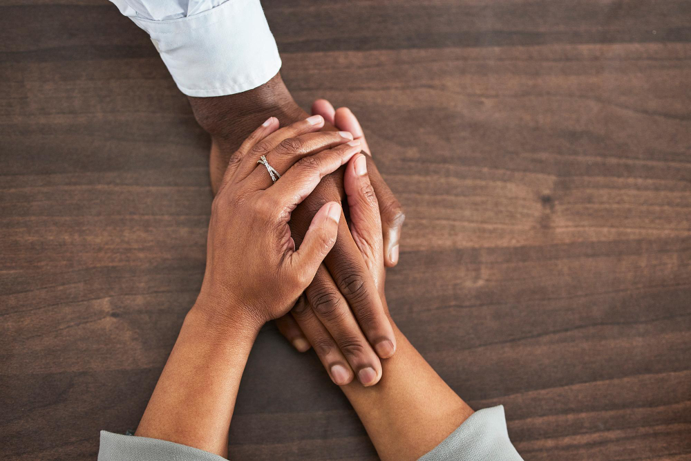 Photo holding hands support and trust with people help and closeup on wood table with communication and relationship above mental health or praying with counselling or worship solidarity and empathy
