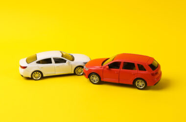 Two mini toy car crash on a yellow background incident car traffic accident