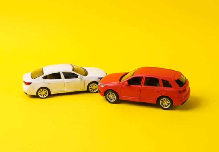 Two mini toy car crash on a yellow background incident car traffic accident