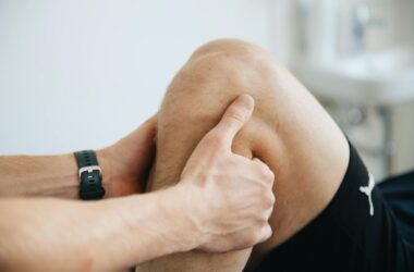Close-up of a physiotherapist massaging a patient's knee during therapy.