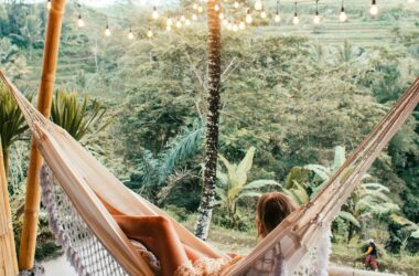 Woman lounging in a hammock on a serene tropical veranda surrounded by nature.