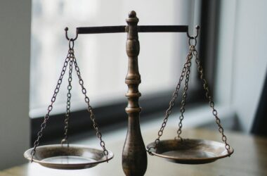Decorative judgement scale and gavel placed on desk in light lawyer office against window
