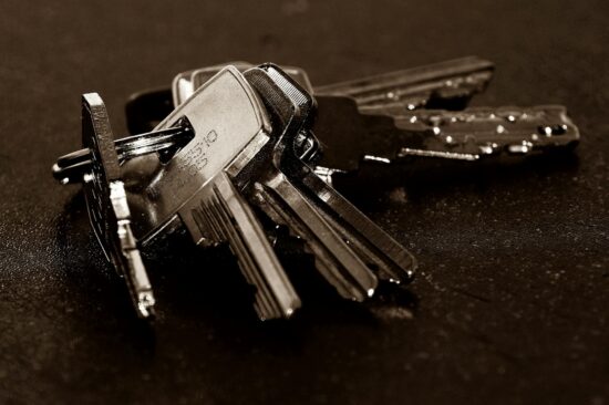 A detailed close-up of a bunch of metallic keys resting on a dark textured surface.